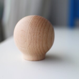 May include: A smooth, round, wooden knob with a light brown color.