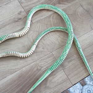 Puede incluir: Dos serpientes de juguete segmentadas de color verde y blanco sobre un suelo de madera. Las serpientes est&aacute;n hechas de pl&aacute;stico y tienen un aspecto realista.