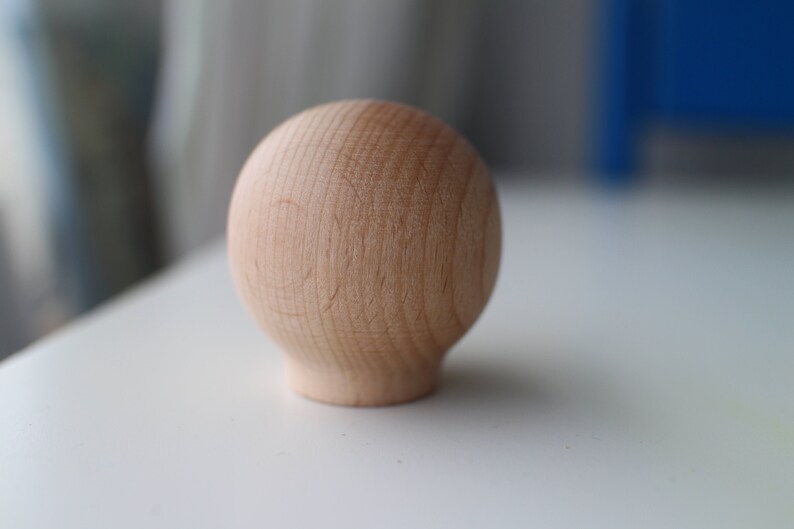 May include: A light brown wooden sphere with a smooth, slightly textured surface.