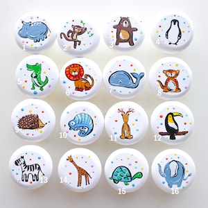 Op de afbeelding: Set van 16 witte ronde knoppen met kleurrijke dierillustraties. De knoppen zijn genummerd van 1 tot en met 16. De dieren zijn een nijlpaard, aap, beer, pinguïn, krokodil, leeuw, walvis, tijger, egel, kameleon, hert, toekan, zebra, giraffe, schildpad en olifant.