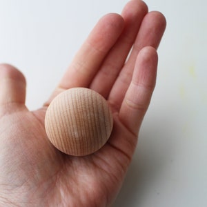 May include: A close-up of a light brown wooden ball with a smooth, slightly textured surface.