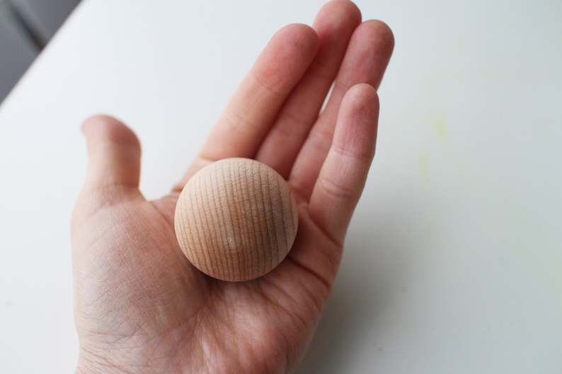 May include: A close-up of a light brown wooden ball with a smooth, slightly textured surface.