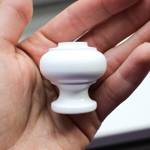 May include: White ceramic cabinet knob with a rounded top and a slightly flared base.