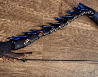 May include: A curved bow-like weapon featuring a textured, weathered copper-colored blade at one end. The handle and frame are wrapped in dark blue material with a series of blue, fin-like protrusions along the upper spine of the curved shaft.