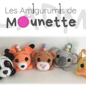 Könnte beinhalten: Fünf gehäkelte Tierplüschtiere mit Holzperlenketten. Die Plüschtiere sind ein Panda, ein Fuchs, ein Bär, ein Koala und eine Ente. Die Plüschtiere sind alle nach vorne gerichtet und haben schwarze Augen. Der Hintergrund ist weiß.