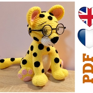 May include: A crocheted yellow cheetah toy with black spots, wearing round black spectacles. The cheetah has a white muzzle and pink paw pads. The image includes a PDF icon.
