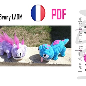 May include: Two crocheted amigurumi toys, one purple with pink hair and one blue with a pink tongue, are sitting on a stone wall. The toys are both looking to the right. The image also includes the text "Bruny LADM" and "PDF" in the top left and right corners, respectively.