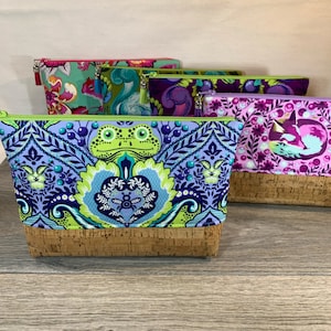 May include: Five colorful zippered pouches with cork bottoms. The pouches feature different patterns, including a green frog, a pink fox, and a floral design.