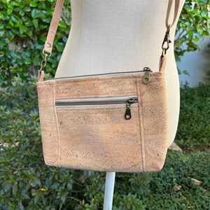 Puede incluir: Un bolso bandolera de corcho marr&oacute;n claro con cierre de cremallera y dos bolsillos delanteros. El bolso tiene una correa larga ajustable.