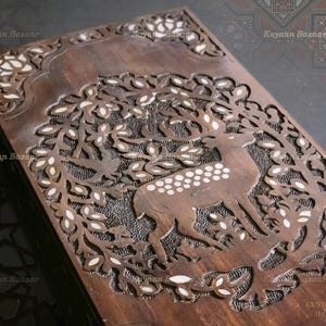 Puede incluir: Una caja de madera con intrincados tallados de un ciervo en una escena de bosque. Los tallados están incrustados con nácar. La caja está etiquetada "KAYANN CUSTOM & ANTIQUE HANDCRAFTED".