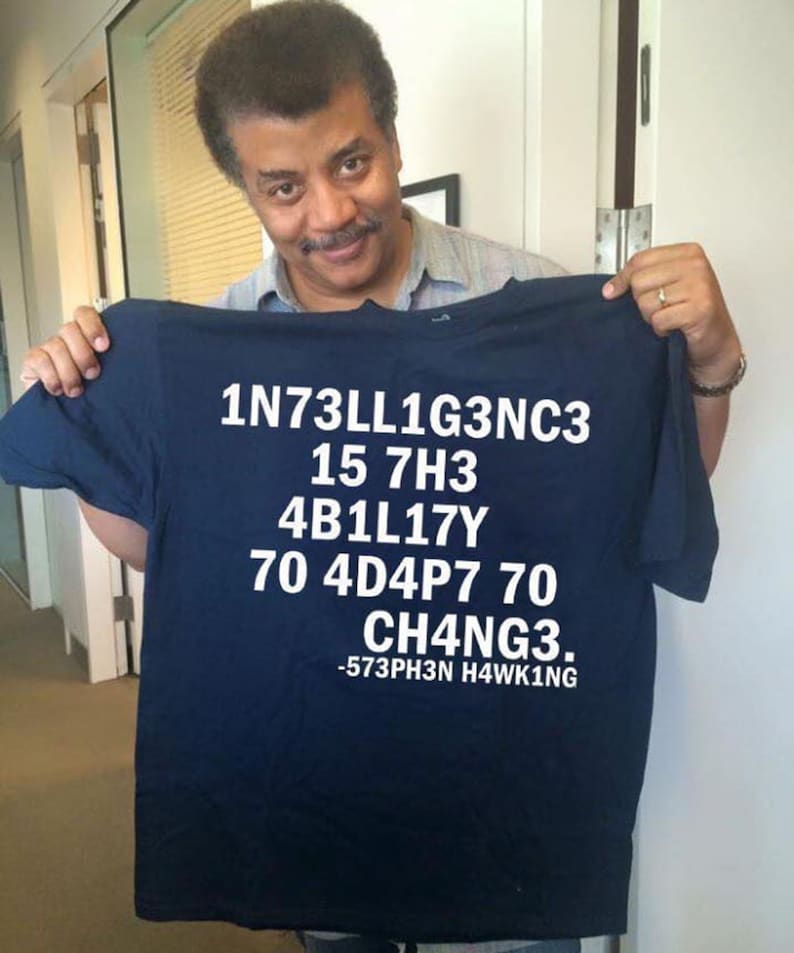May include: A navy blue t-shirt with white text that reads "1N73LL1G3NC3 15 7H3 4B1L17Y 70 4D4P7 70 CH4NG3. -573PH3N H4WK1NG"