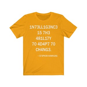 May include: A yellow t-shirt with white text that reads "1N73LL1G3NC3 15 7H3 481LL17Y 70 4D4P7 70 CH4NG3. - 573PH3N H4WK1NG"