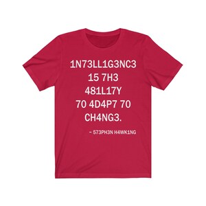 May include: Red t-shirt with white text that reads "1N73LL1G3NC3 15 7H3 481LL17Y 70 4D4P7 70 CH4NG3. - 573PH3N H4WK1NG"