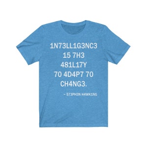 May include: A light blue t-shirt with white text that reads "1N73LL1G3NC3 15 7H3 481L17Y 70 4D4P7 70 CH4NG3. ~ 573PH3N H4WK1NG"