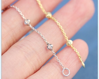 Può includere: Due catene delicate con piccoli ciondoli rotondi testurizzati. Una catena è d'argento e l'altra è d'oro.