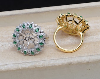 May include: Two rings with a floral design. One ring is silver with green and white stones. The other ring is gold with green stones.