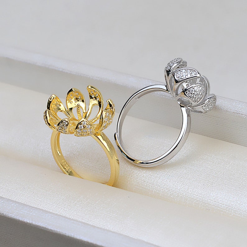 May include: Two rings with a flower design, one is gold and the other is silver. Both rings are adorned with small clear stones.