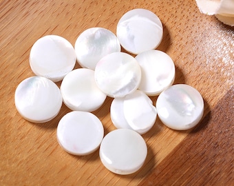 Peut inclure: Un ensemble de boutons ronds en nacre blanche. Les boutons sont lisses et ont un léger éclat iridescent.