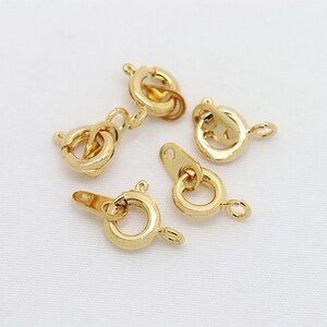 以下が含まれることがあります： ジュエリー作りのための、金色の金属製のロブスタークラスプが5つ。クラスプは丸型で、バネ式のメカニズムになっています。