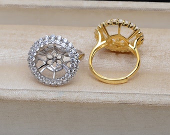 May include: Two silver and gold rings with a round, open design set with clear stones. The rings are on a white surface.