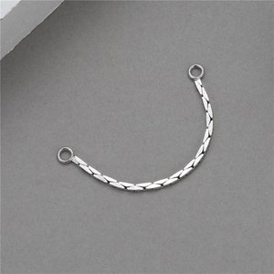 Può includere: Estensione per catena in argento con due anelli di giunzione. La catena è composta da piccoli pezzi piatti e collegati.