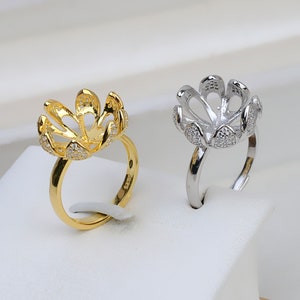 May include: Two pearl ring settings, one gold and one silver, with a flower-shaped design and small clear stones.