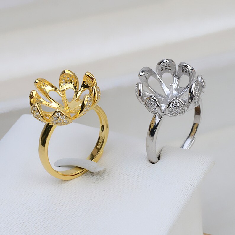 May include: Two pearl ring settings, one gold and one silver, with a flower-shaped design and small clear stones.