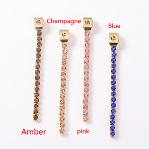 May include: Five gold-toned chains with different colored crystals. The chains are labeled "Amber", "Champagne", "Pink", "Blue".