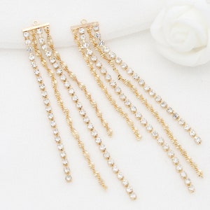 May include: A pair of gold-tone dangle earrings with multiple strands of clear rhinestones.