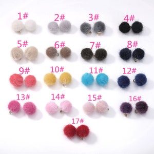 May include: Assortment of 17 pairs of faux fur pom poms in various colours, including white, grey, black, brown, yellow, blue, pink, red, and purple. Each pom pom has a gold loop for attaching.