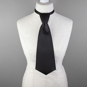 May include: A black satin tie on a white mannequin.