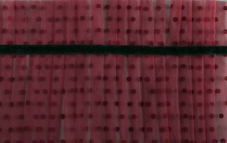 Puede incluir: Tela de tul roja con estampado de lunares y ribete de cinta de terciopelo negro.