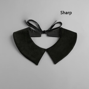 May include: Black velvet collar with a bow tie closure. The collar has a classic design with pointed edges and a soft texture. The word "Sharp" is printed in black on the upper right side of the image.