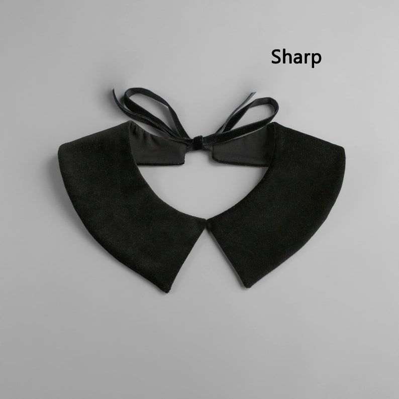 May include: Black velvet collar with a bow tie closure. The collar has a classic design with pointed edges and a soft texture. The word "Sharp" is printed in black on the upper right side of the image.