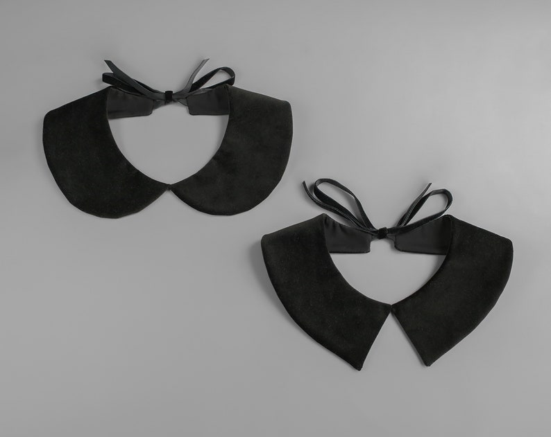 May include: Two black velvet Peter Pan collars with a matching black ribbon tie. The collars are displayed on a gray background. The collars have a soft, rounded shape.