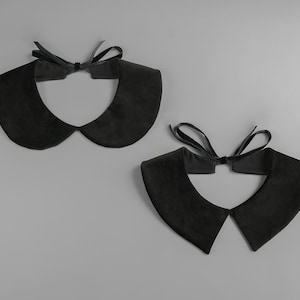 May include: Two black velvet Peter Pan collars with a matching black ribbon tie. The collars are displayed on a gray background. The collars have a soft, rounded shape.