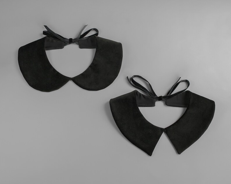 May include: Two black velvet Peter Pan collars with a matching black ribbon tie. The collars are displayed on a gray background. The collars have a soft, rounded shape.