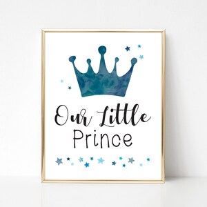 K&ouml;nnte beinhalten: Eine blaue Aquarellkrone auf wei&szlig;em Hintergrund mit dem Text "Our Little Prince" in schwarzer Kursivschrift. Kleine blaue Sterne sind um die Krone herum verstreut.