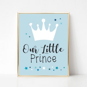 May include: A light blue printable sign with a white crown and the text "Our Little Prince" in black script. The background is decorated with blue and white stars.