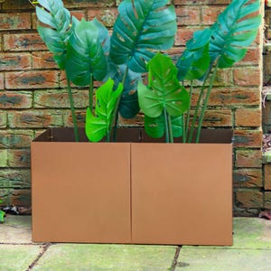 May include: A pair of copper-coloured metal planters with a modern design. The planters are filled with green leafy plants.