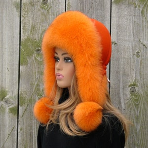 May include: A bright orange fur hat with two pom-poms. The hat has a long, fluffy brim and is made of real fur.