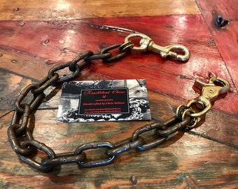 May include: A heavy duty chain keychain with two brass clasps. The chain is made of thick, dark metal links. The keychain is handcrafted by Chris Stithem, as indicated on the business card in the image.  The business card reads "Knucklehead Chains, Custom Jewelry, Handcrafted by Chris Stithem, Facebook.com/knuckleheadchains, etsy.com/shop/knuckleheadchains".