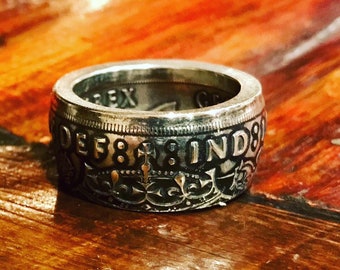 May include: A silver ring made from a vintage coin. The coin features the text "DEF 8 IND 80" and a crown with a cross.