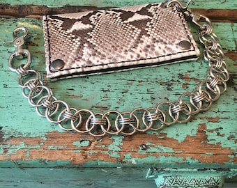 May include: A silver chain wallet with a snake skin pattern. The chain is made of interlocking rings.
