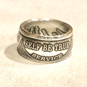 Può includere: Anello d'argento con le parole "Self Be True Service" incise sulla fascia.