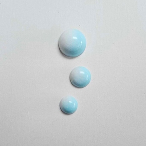 Peut inclure: Trois ornements ronds peints en dégradé de bleu et de blanc. Les ornements sont de tailles différentes et sont disposés verticalement sur un fond blanc.