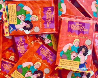 May include: A collection of unopened trading card packs featuring Disney's "The Hunchback of Notre Dame." The packs are orange with character illustrations and the title. Each pack contains 11 cards, a finger puppet, and more.