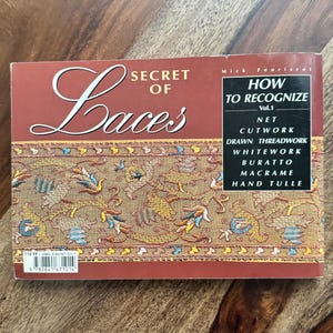 May include: A book titled "Secret of Laces" by Mick Fouriscot, volume 1, about how to recognize different types of lace, including net, cutwork, drawn threadwork, whitework, buratto, macrame, and hand tulle.