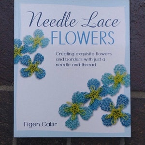 May include: Book cover with the title "Needle Lace Flowers" and the subtitle "Creating exquisite flowers and borders with just a needle and thread". The cover features a blue background with several blue and yellow needle lace flowers.