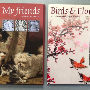 May include: Two books with red covers and white text. The book on the left is titled "My Friends" by Kumiko Nakazaki and features a painting of a dog and several cats. The book on the right is titled "Birds & Flowers" by Kumiko Nakazaki and features a painting of a cherry blossom branch with two birds.